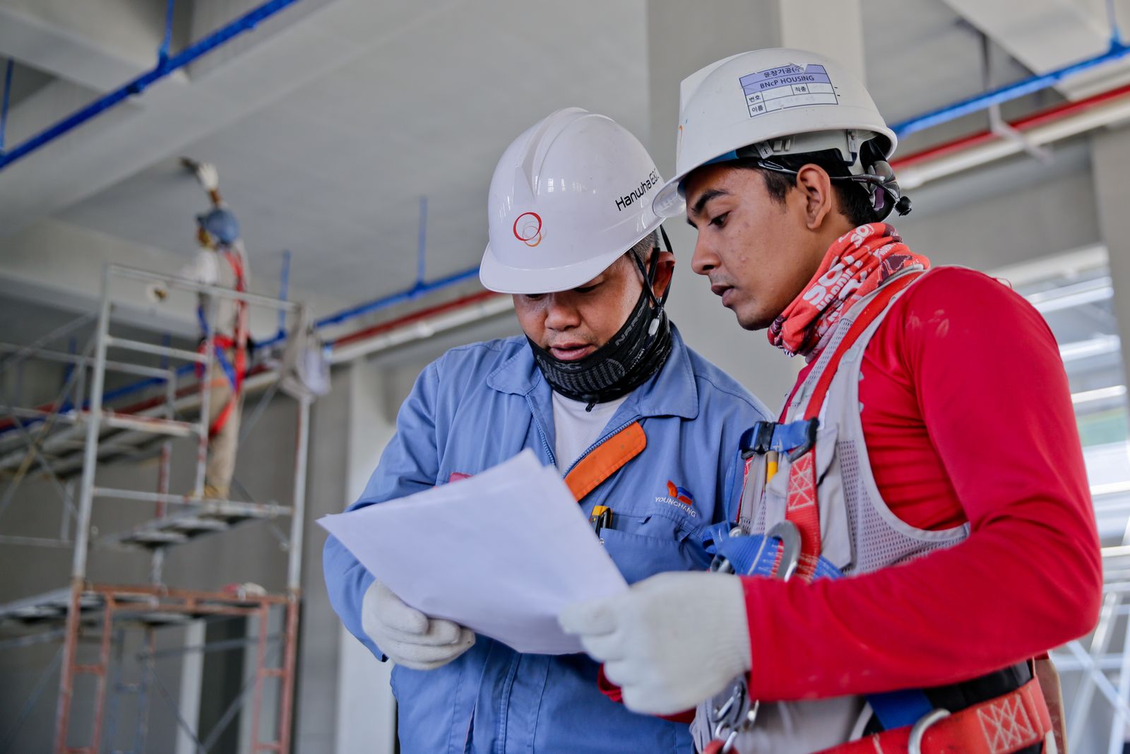 Two construction workers in hard hats checking paperwork on site