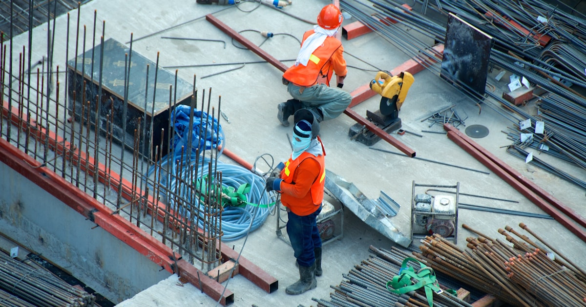 Construction site manager reviewing plans on a busy building site